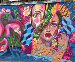 Murale artistique vivante avec le portrait d'une femme entourée de fleurs exotiques et de flamants roses.